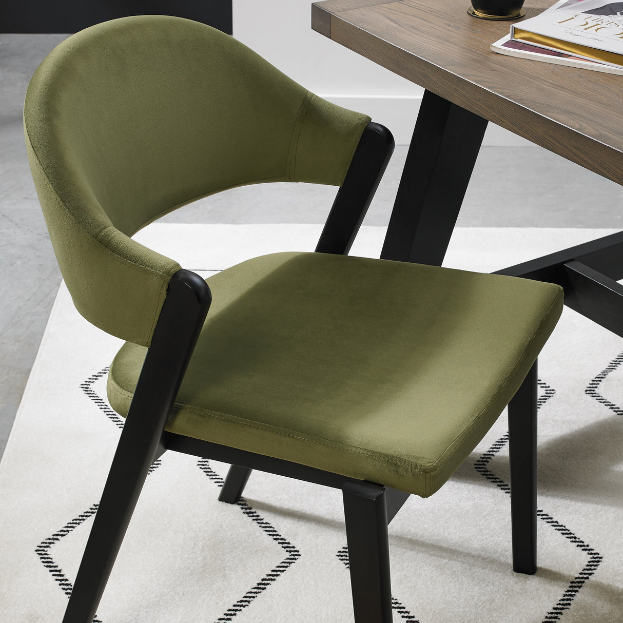 A close and angled image of the Candice Velvet dining chairs with a curved back and dark oiled legs