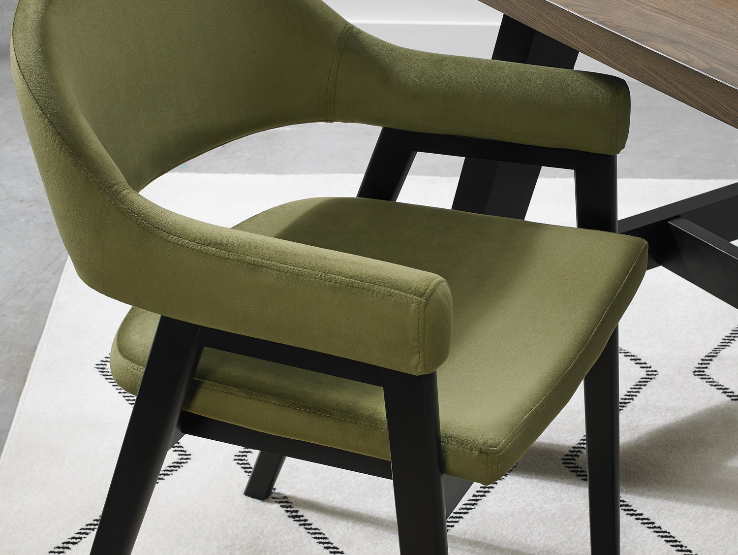 Up-close image of the Candice Velvet dining chairs with curved back, armrests, and dark legs.
