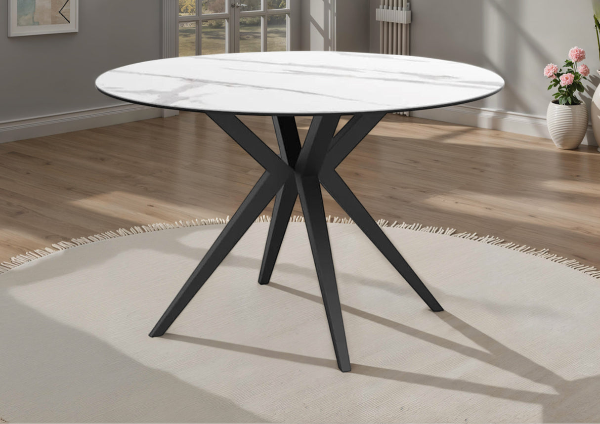 Round dining table with white ceramic top and black metal legs in a room setting.