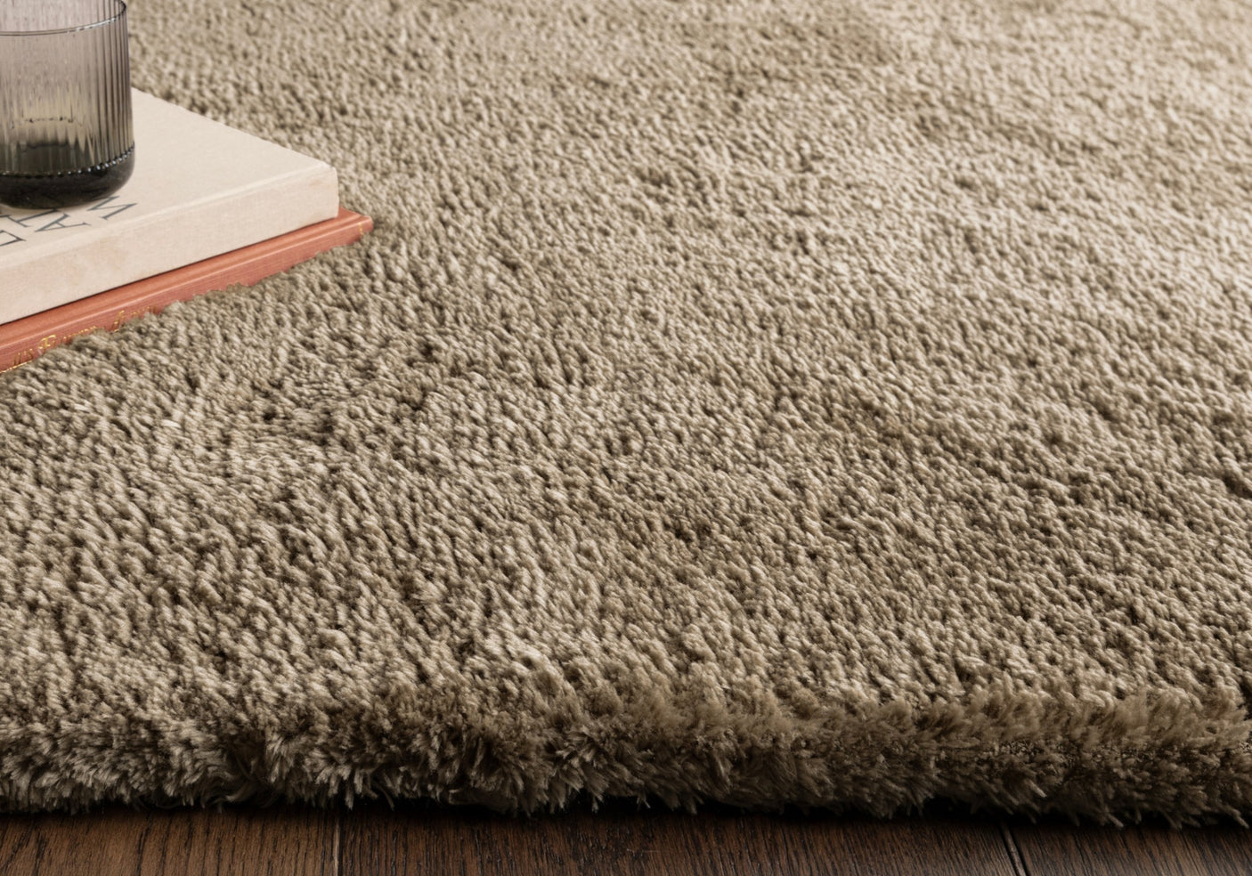 Close up of taupe rug on wooden floor.