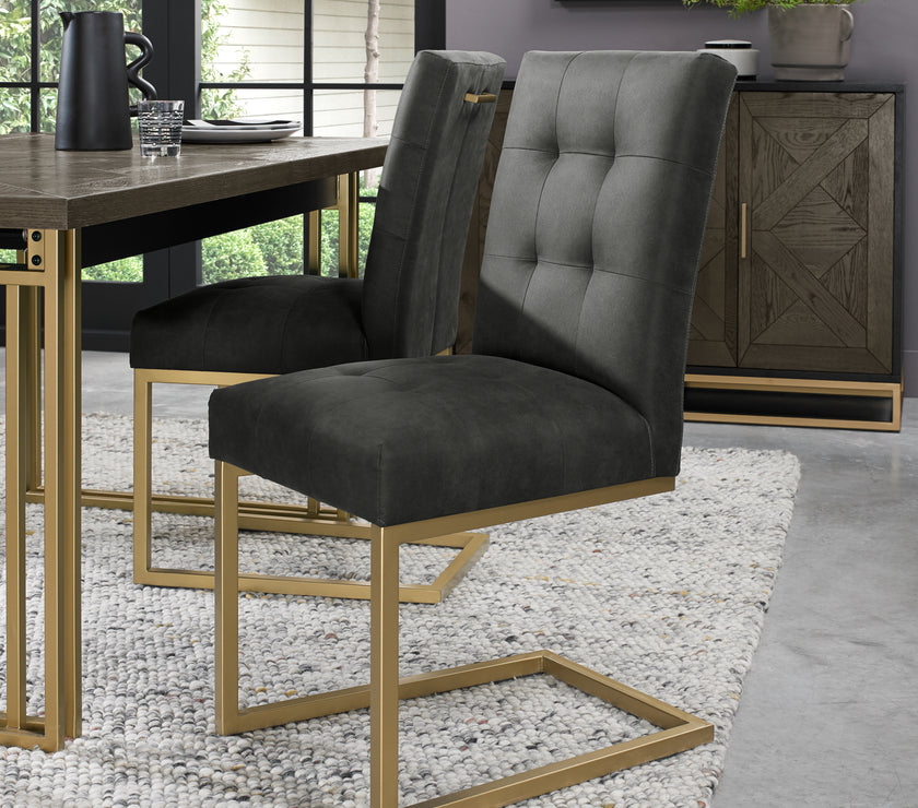 Angled view of the Lindos Fabric Dining Chairs with black square-stitched upholstery and brass legs.