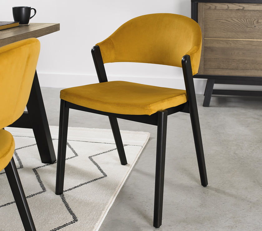 Angled and up close image pf the Candice Velvet Dining Chair with curved back and dark legs.