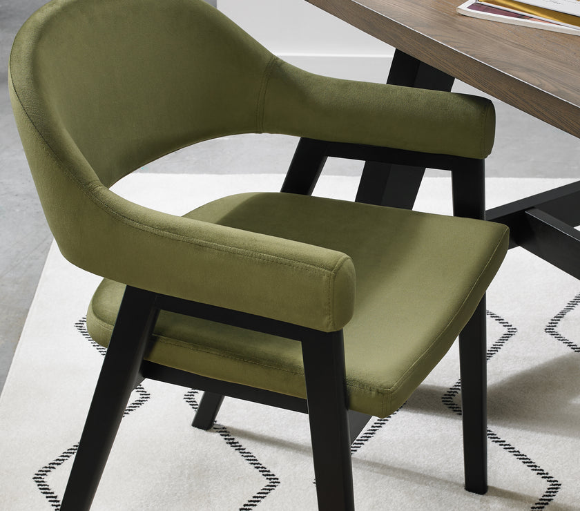 Up-close image of the Candice Velvet dining chairs with curved back, armrests, and dark legs.