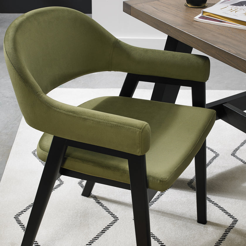 Up-close image of the Candice Velvet dining chairs with curved back, armrests, and dark legs.