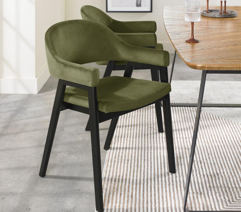 Angled image of the Candice Velvet dining chairs with curved back, armrests, and dark legs.