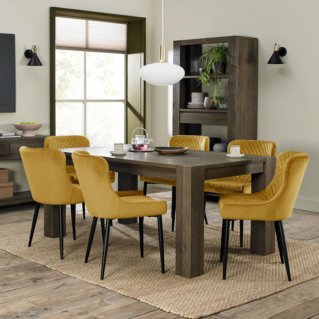 image of our Lozanne Velvet Dining Chairs in mustard with diamond stitching and black leg styled with one of our stunning dining tables
