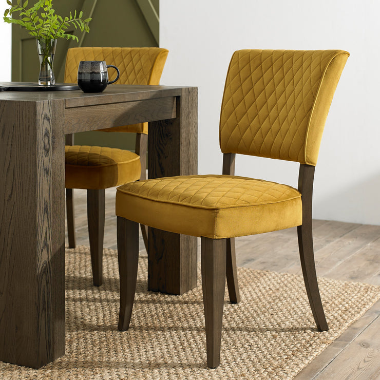 Up-close and angled image of the Landon Fumed Oak Dining Chairs with dark oak frame and mustard velvet seat.