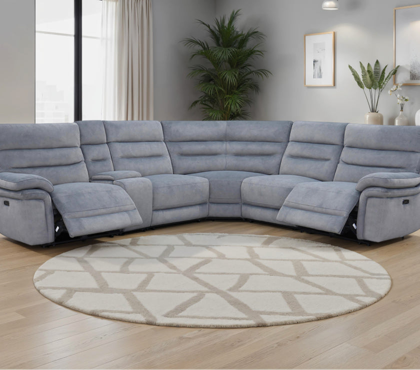 Grey recliner sofa in a living room with a round rug and décor elements.
