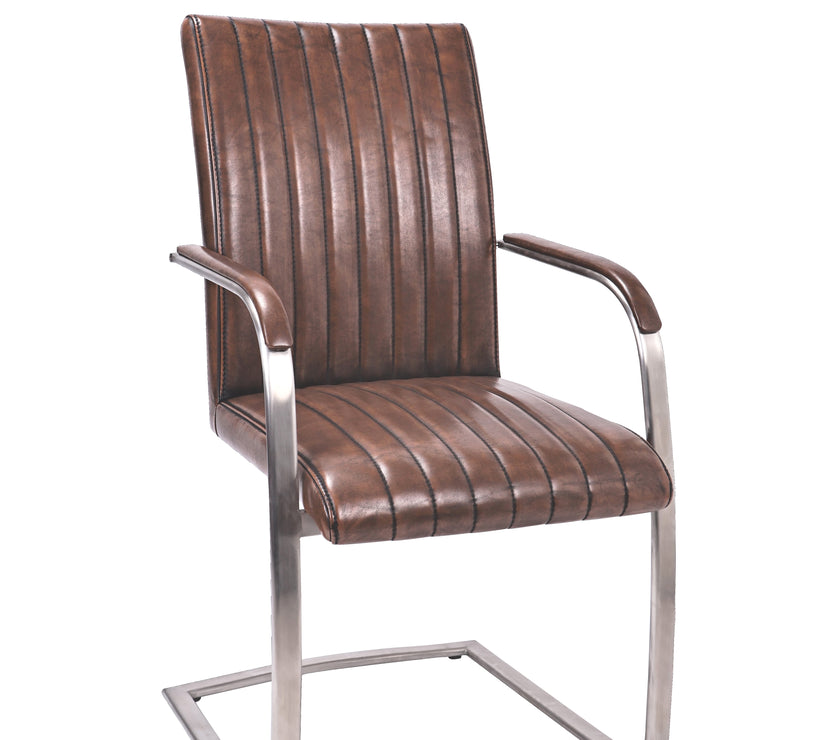 Angled view of the Triumph Cantilever Faux Leather Dining Chairs with armrests and steel legs.