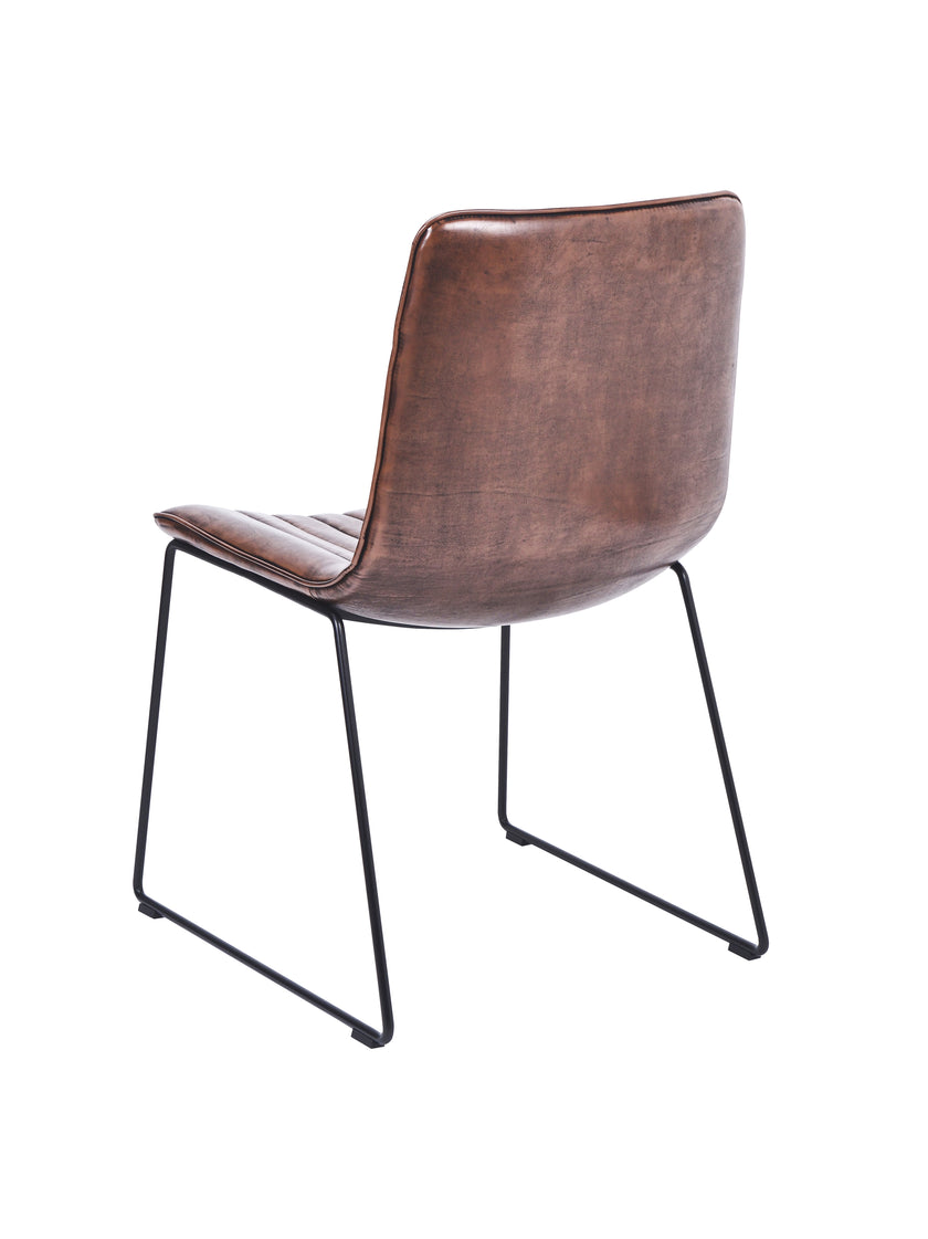 Back and angled view of the Atlas Faux Leather Dining Chairs with curved back, tan upholstery, and black metal legs.