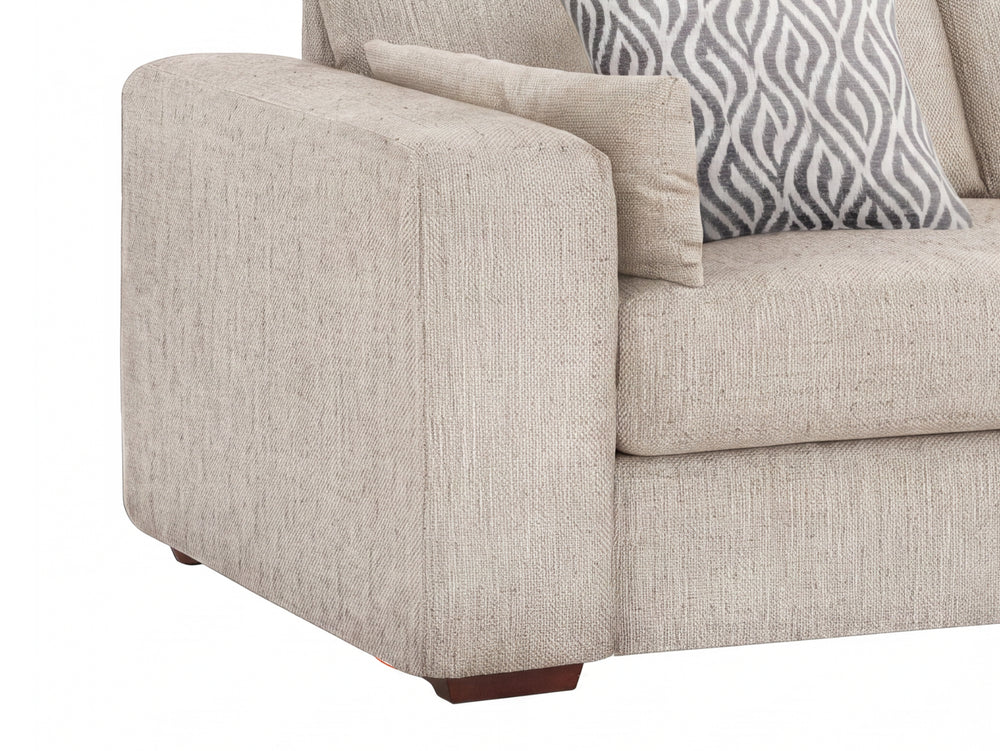 Close-up of a beige upholstered sofa corner with a patterned gray and white accent pillow on a white background.