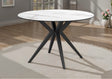 Round dining table with white ceramic top and black metal legs in a room setting.