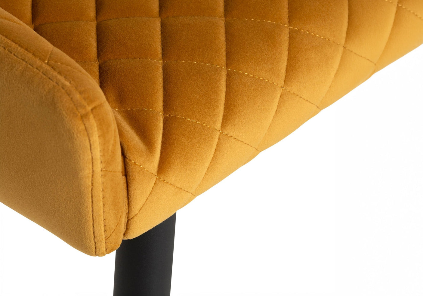 Close-up of a mustard yellow quilted chair with a black leg on a white background