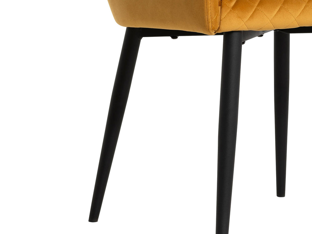 Close-up of a mustard yellow chair with black legs on a white background