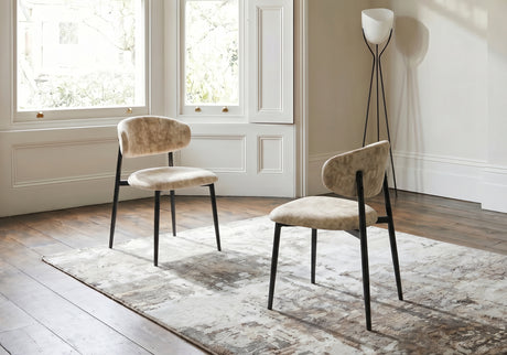 Two beige chairs with black legs in a room with large windows and a lamp.