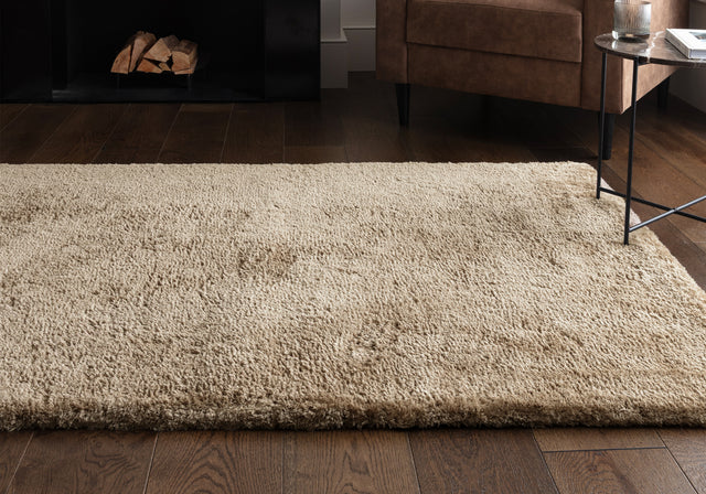A taupe rug on a wooden floor.