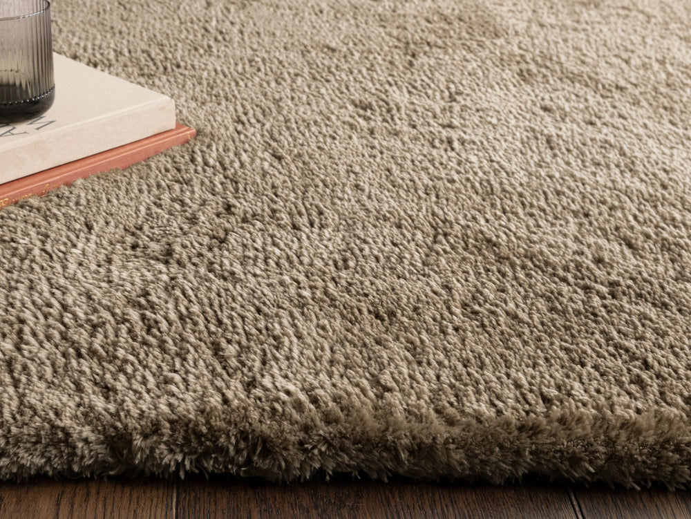 Close up of taupe rug on wooden floor.