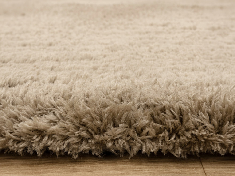Close up of taupe rug on wooden floor.