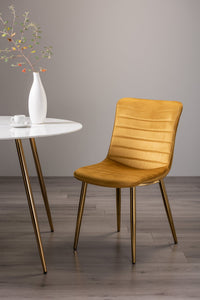 Angled image of the Aso Velvet Dining Chairs with tapered back, light-reflecting velvet, and golden tapered legs.