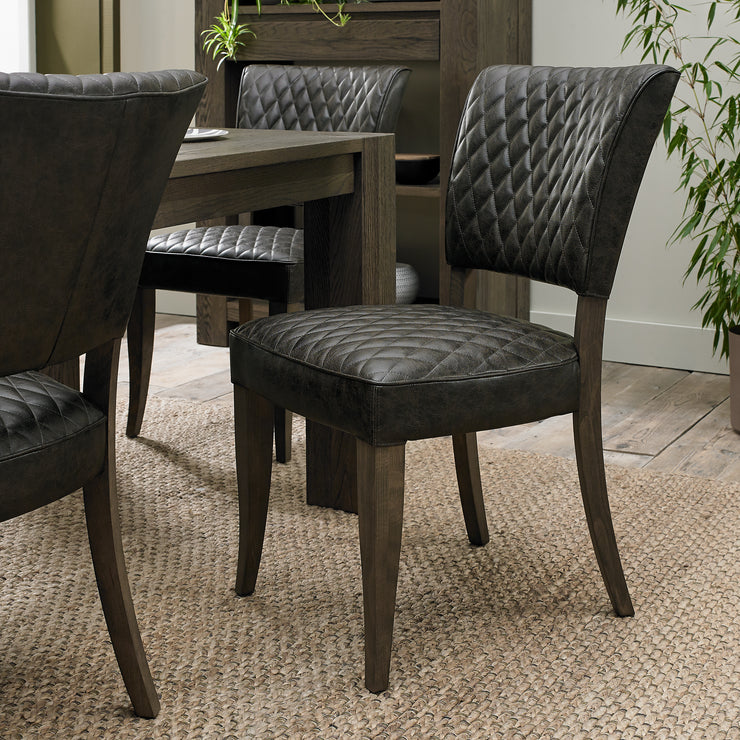 Angled view of the Landon Fumed Oak Dining Chairs Saddle Faux Leather with dark oak frame.
