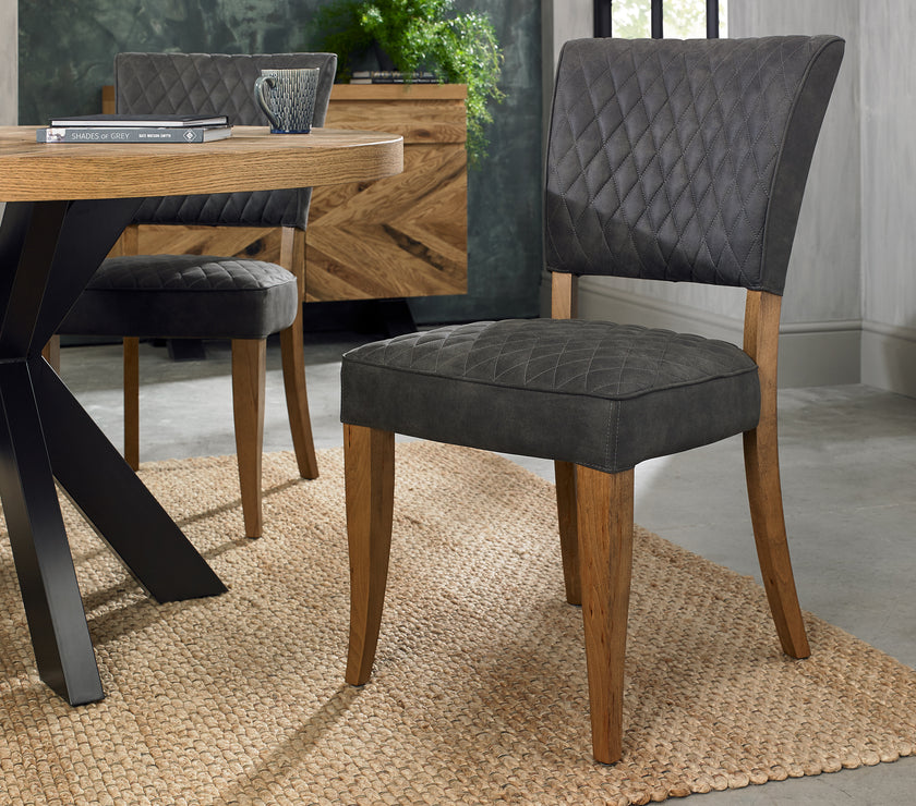 Angled view of the Landon Rustic Oak Dining Chairs with lightly oiled oak frame and dark grey fabric seat.