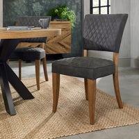 Angled view of the Landon Rustic Oak Dining Chairs with lightly oiled oak frame and dark grey fabric seat.