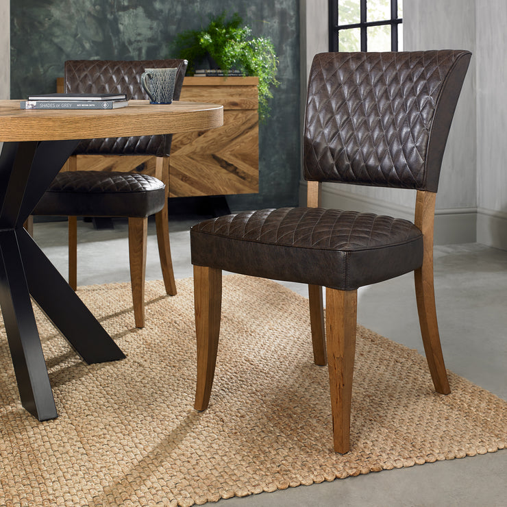 Angled image of the Landon Rustic Oak Dining Chairs with lightly oiled oak frame and saddle brown faux leather seat.