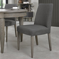 Angled view of the Marilyn Fabric Dining Chairs with slate grey upholstery and silver grey tapered legs.