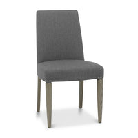 Angled, front and close view of the Marilyn Fabric Dining Chairs with slate grey upholstery and silver grey tapered legs.