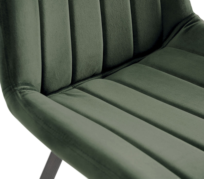 Close up view of the Savio Dining Chairs in green velvet with vertical stitching and metal legs.