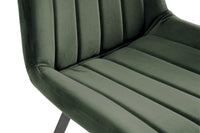 Close up view of the Savio Dining Chairs in green velvet with vertical stitching and metal legs.