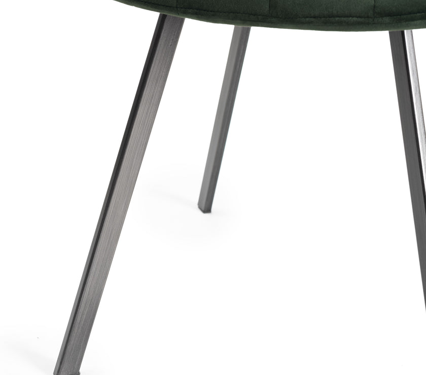 View of the legs of the Savio Dining Chairs in green velvet with vertical stitching and metal legs.