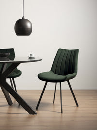 Long distance view of the Savio Dining Chairs in green velvet with vertical stitching and metal legs.