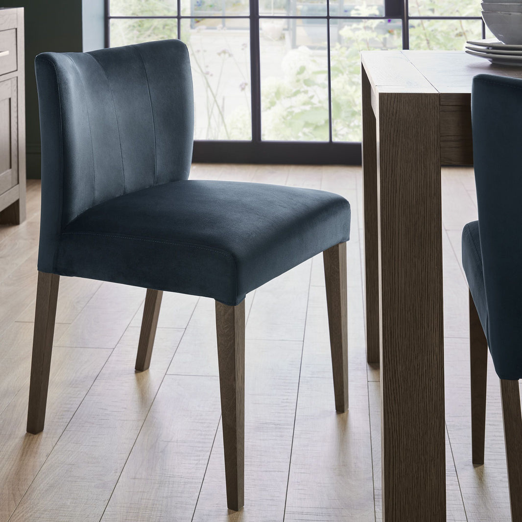 Angled image of the Turner Dark Oak Dining Chairs with foam cushion, fabric upholstery, and tapered dark oak legs.